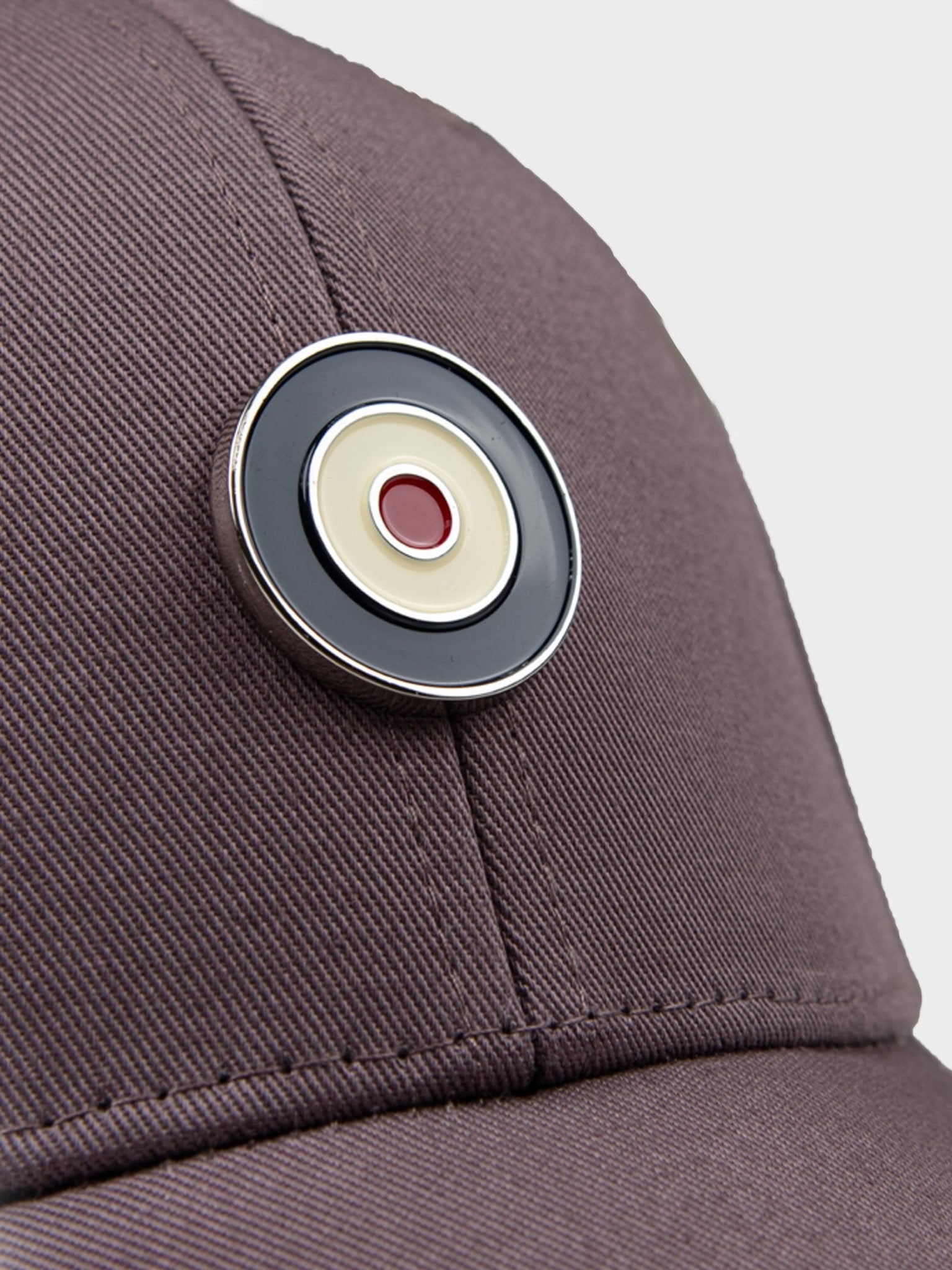 Close-up detail of Ben Sherman Metal Target Badge Cap in Cocoa Powder showing metal target badge emblem with red centre