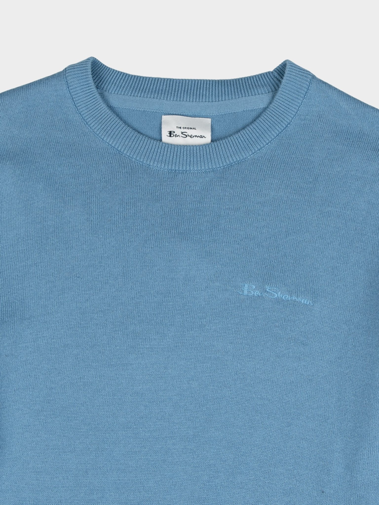 Close-up of Ben Sherman Crew Neck Knit sweater in Blissful Blue showing ribbed neckline, branded neck label and tonal chest branding