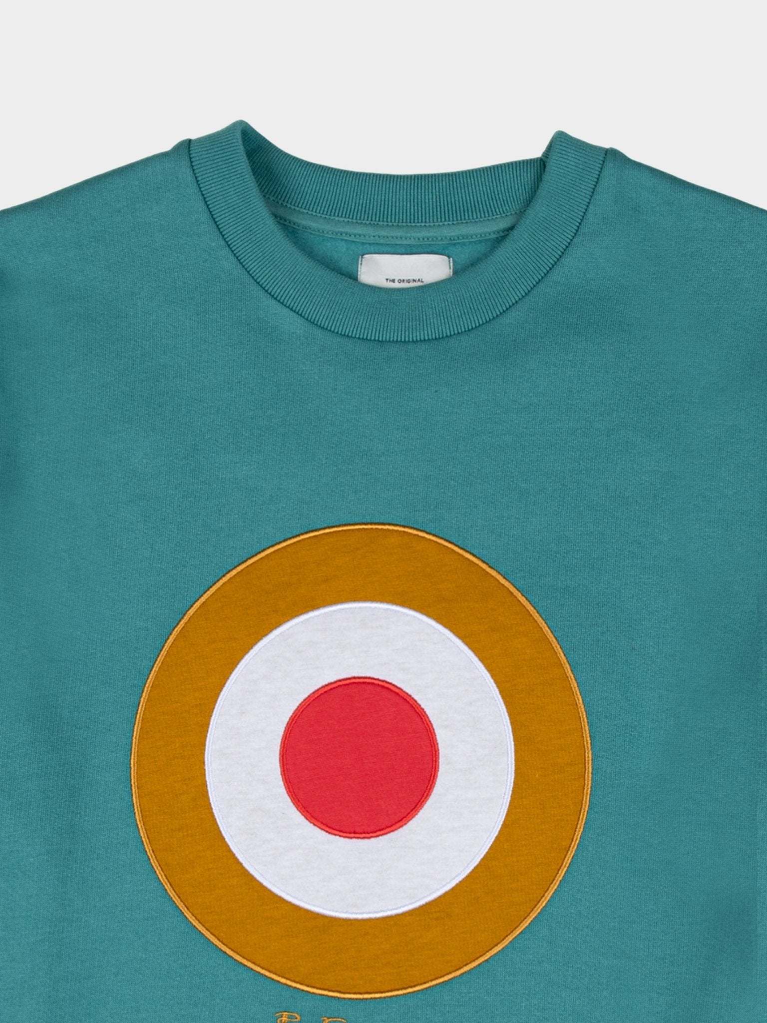 Ben Sherman Target EMB Crew Fleece in Aqua Teal, close-up detail of embroidered gold, white and red target roundel and branded neck label