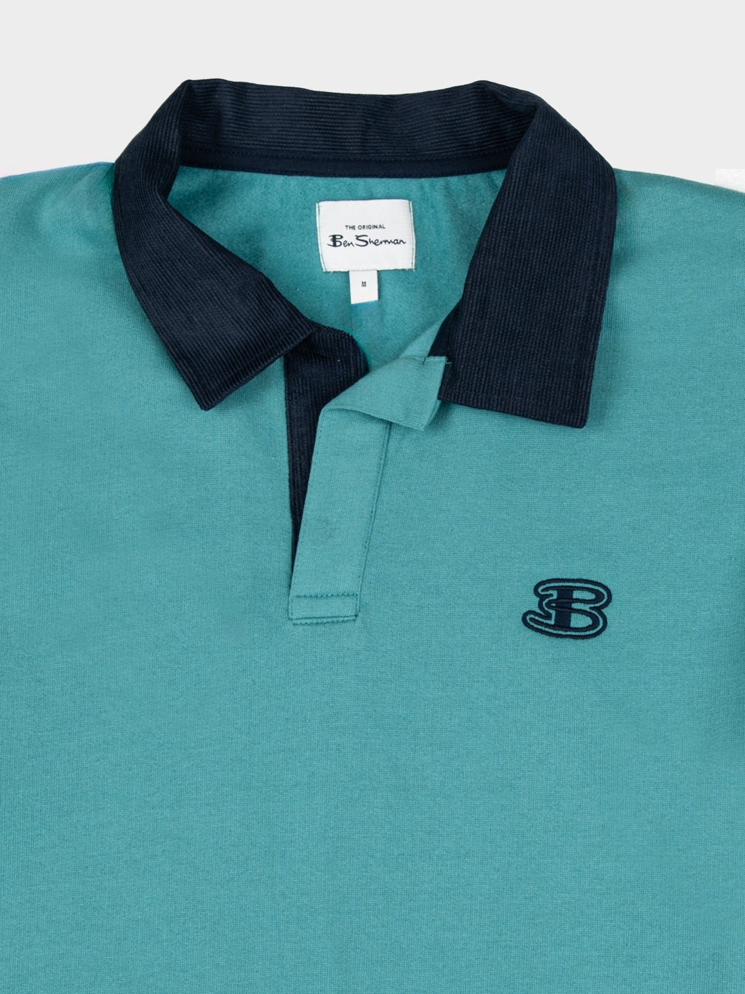Close-up detail of Ben Sherman men's polo sweater in Aqua Teal – dark contrast polo collar, embroidered B logo on chest and Ben Sherman woven label on premium cotton knit